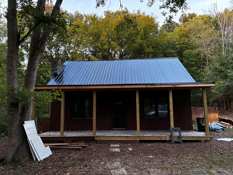 Same cabin after, with a blue standing seam metal roof and new porch
