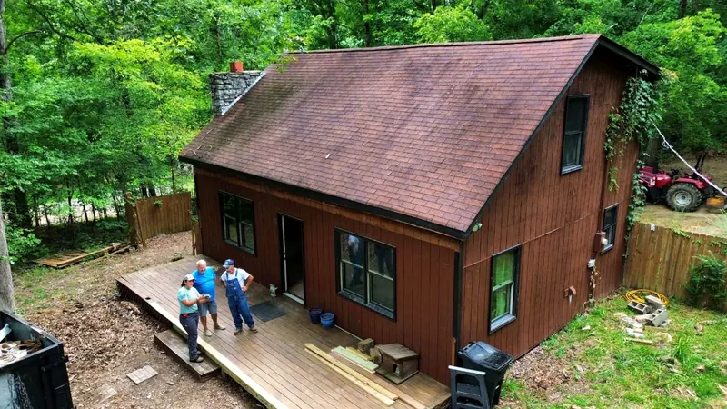 Cabin before, with a worn brown shingle roof