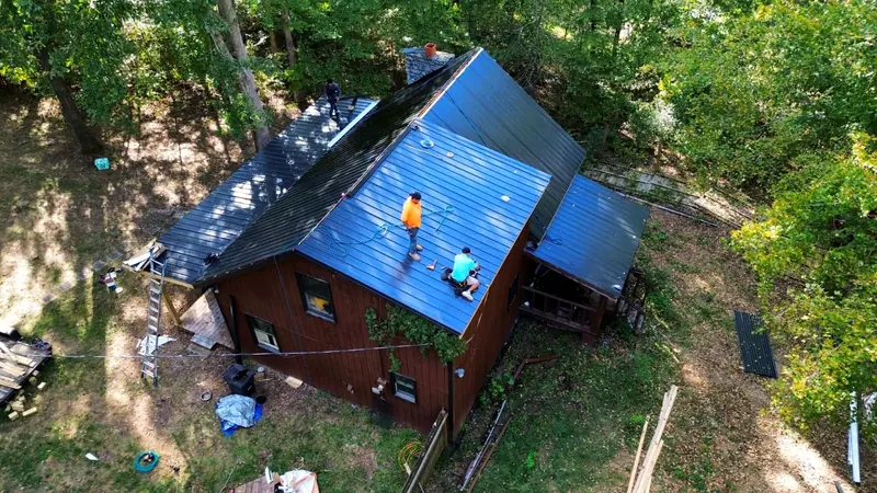 TRS crew installing a blue metal roof, seen from the drone